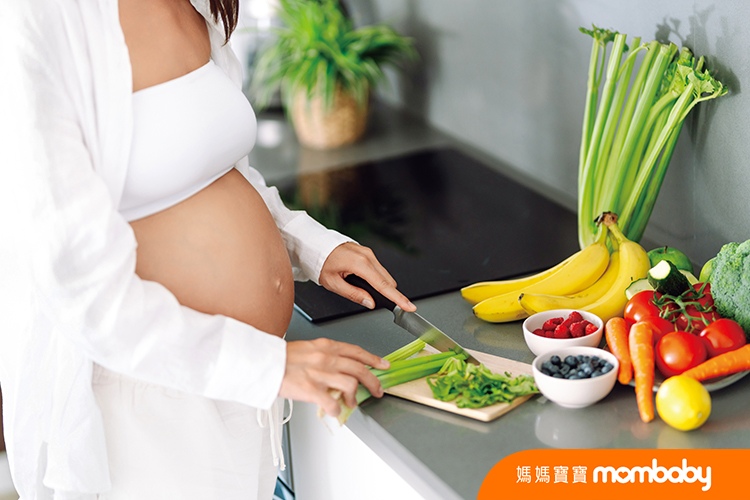 A,Young,Pregnant,Woman,Chops,Celery,While,Standing,In,A